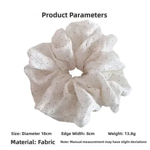 Detail view of a white polka dot scrunchie showing 18cm diameter and fabric texture