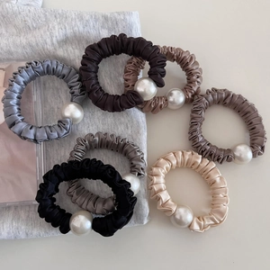 Detail of satin pearl hair ties showing high-elastic pleated fabric in neutral tones