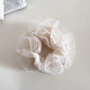 Détail d'un chouchou en organza à couches avec bords plissés et volants couleur crème
