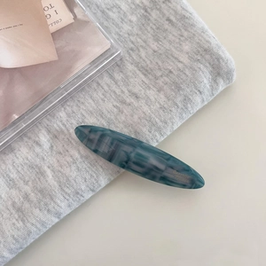 Detailed macro view of the marble-textured blue acetate hair clip with gold logo