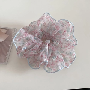 Détail du chouchou en organza floral avec liseré bleu et texture plissée délicate