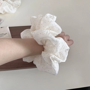 White bubble seersucker hair scrunchie with black polka dots on a wrist
