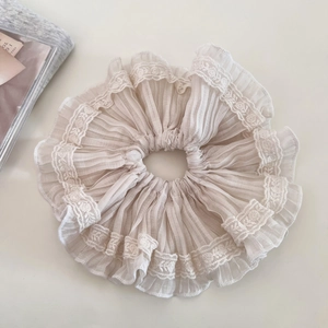 Detailed macro view of beige pleated fabric scrunchie with intricate lace edging details