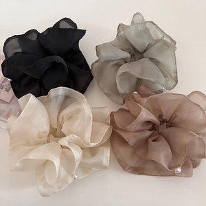 Detail view of four-color layered mesh scrunchies with elegant pearl accents on a light background