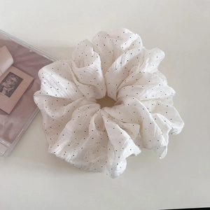 Macro view of white polka dot scrunchie made of soft chiffon fabric for hair