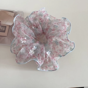 Détail d'un chouchou en mousseline florale avec motifs pastels et bordure bleue claire
