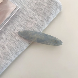 Close-up of gray-blue marble acetate hair clip with golden Barrette la France logo