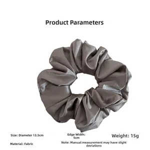 Detail view of large grey satin scrunchie with 13.5cm diameter and pleated fabric texture