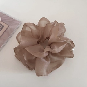 Detail view of champagne mesh scrunchie with white pearl accents and soft pleats