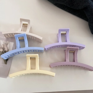 Close-up of five rectangular matte hair claws in cream, blue, yellow and purple tones