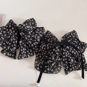 Detail of floral chiffon bow hair clip with black ribbons and delicate pearl pendants