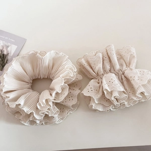 Elegantes Set aus beigen Spitzen- und Falten-Haargummis auf einem schlichten Tisch