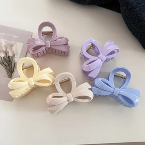 Close-up of five colorful bow-shaped matte resin hair claws in soft pastel colors