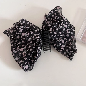 Detail of floral chiffon bow hair claw clip with romantic pink flower pattern and black base