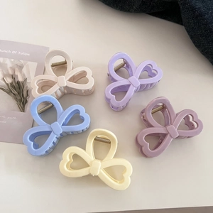Close-up of heart-shaped bow hair claws in five pastel macaron colors with matte finish