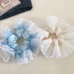 Detail of oversized polka dot scrunchies with white lace edges in blue and cream colors