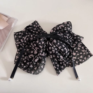 Detail of a large chiffon floral bow hair claw clip with ribbons and pearl drops