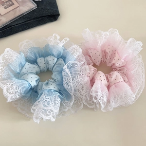Detailed view of oversized polka dot hair scrunchies with white lace trim in blue and pink