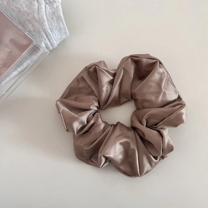 Close-up of champagne gold satin scrunchie with metallic luster and pleated texture