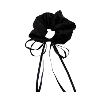 Elegant black satin bow hair scrunchie with long ribbons on a plain white background