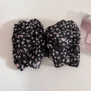 Detail of black chiffon hair claw clip with pink floral patterns and a ribbon bow