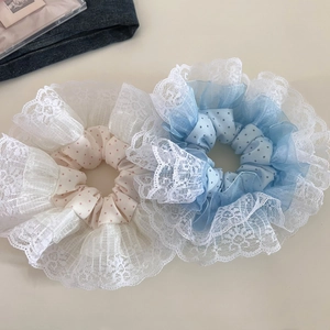 Detailed view of oversized pink and blue polka dot hair scrunchies with white lace edges