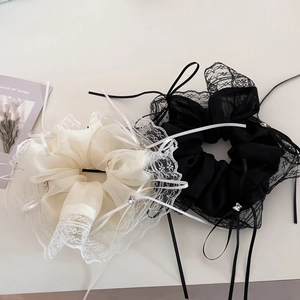 Close-up of lace scrunchies with ribbon bows and rhinestones in black and beige