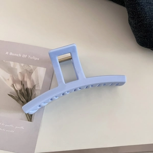 Close-up of light blue matte hair claw clip with spring detail on denim background