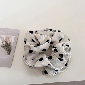 Detailed close-up of a large black polka dot scrunchie made of breathable chiffon fabric