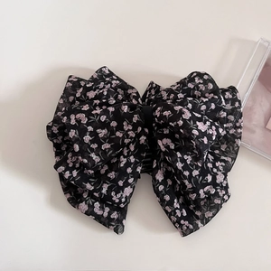 Detail view of large black chiffon hair claw with delicate pink floral pattern and bow
