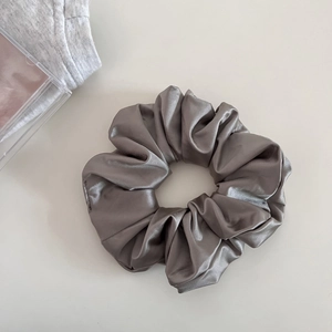 Macro shot of large metallic grey satin scrunchie with glossy texture and elegant folds