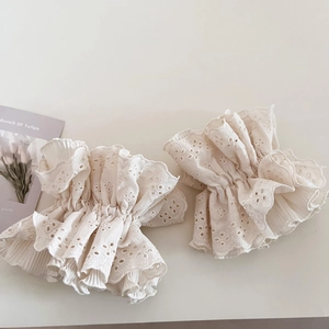 Nahaufnahme von beigem Spitzen-Haargummi mit Blumenstickerei und plissierten Rüschendetails