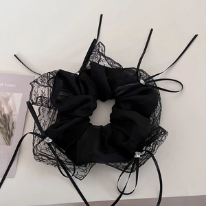 Close-up of black lace scrunchie with ribbon bows and heart crystal accents
