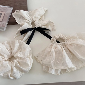 Close-up of vintage cream lace scrunchies with intricate floral embroidery and silk bow