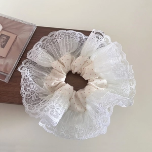 Close-up of fluffy oversized polka dot scrunchie with layered white lace edges