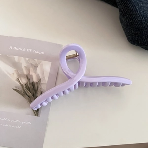 Detailed view of a pastel purple hair claw clip with a minimalist crisscross curved design