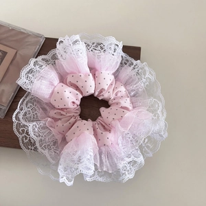 Detailed view of pink polka dot scrunchie with layered white lace embroidery edge
