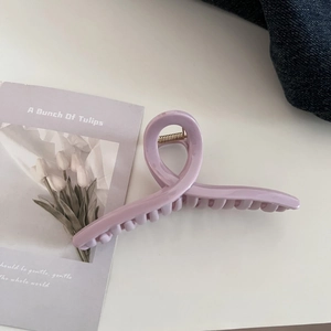 Close-up of lavender purple matte hair claw clip with golden spring on white surface