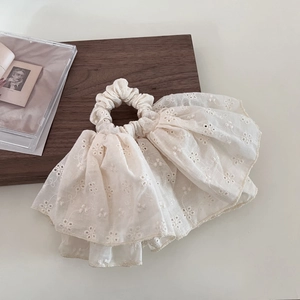Close-up of cream lace scrunchie featuring delicate floral embroidery and scalloped edges