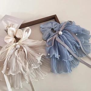 Détail de chouchous plissés bleu clair et beige avec perles et longs rubans