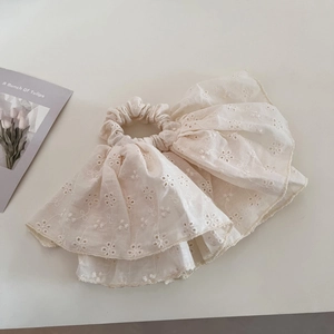 Detail of cream lace scrunchie featuring floral embroidery and ruffle textures