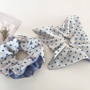 Detailed close-up of blue polka dot hair scrunchie set on a clean white background