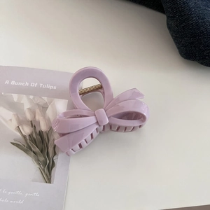 Detail view of a pale purple bow hair claw clip with a gold metal spring mechanism
