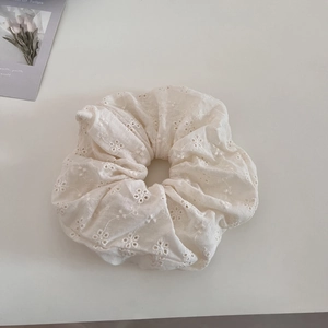 Close-up of white lace hair scrunchie with delicate floral hollow embroidery detail