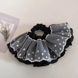 Detail of elegant black and white polka dot lace scrunchie with layered mesh ruffle design