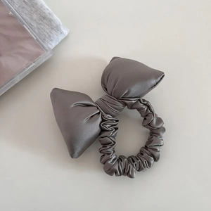 Detail view of smooth grey satin puffy bow scrunchie for elegant ponytail hairstyles