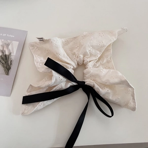 Detailed macro view of white lace embroidery scrunchie with black silk ribbon bow