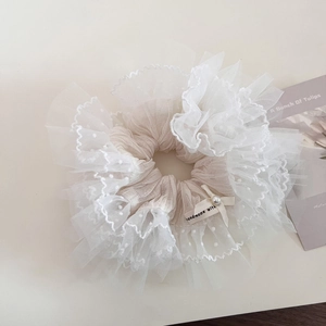 Close-up of cream lace scrunchie with layered mesh, pearl detail, and ribbon accent