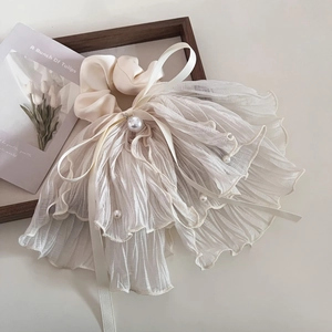Détail d'un chouchou plissé crème en mousseline avec perles blanches et nœud élégant