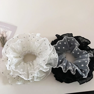 Close-up of black and white tulle hair scrunchies with polka dots and ruffled lace edges